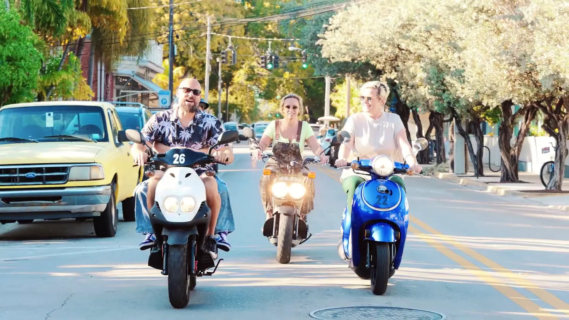 Friends riding scooters down a Key West street